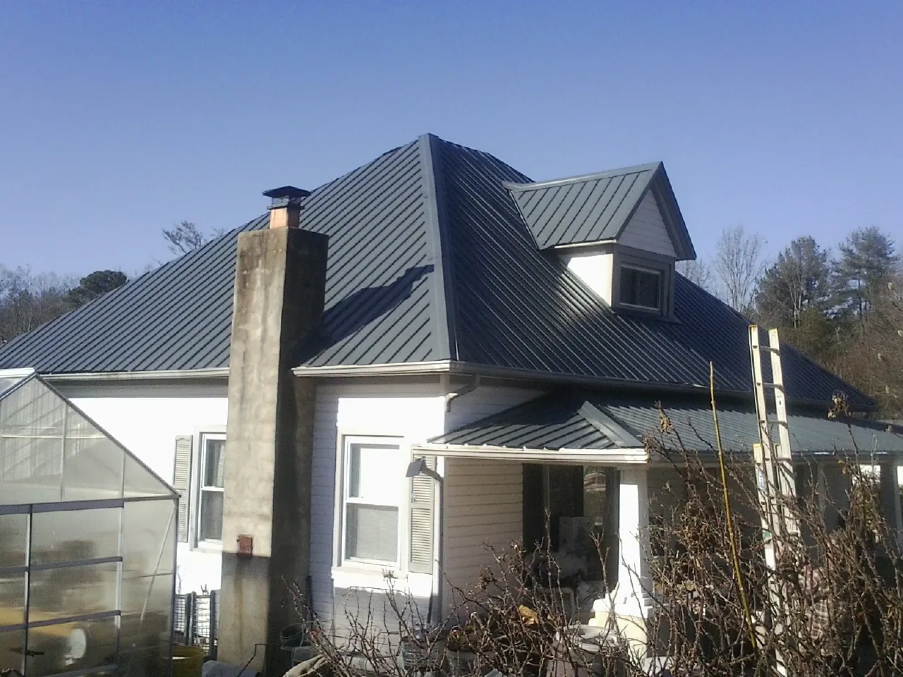 Dark blue standing seam metal roof on a white farmhouse with dormer — Slate & Tile Roof Repair by Roofing Brothers in New Gloucester