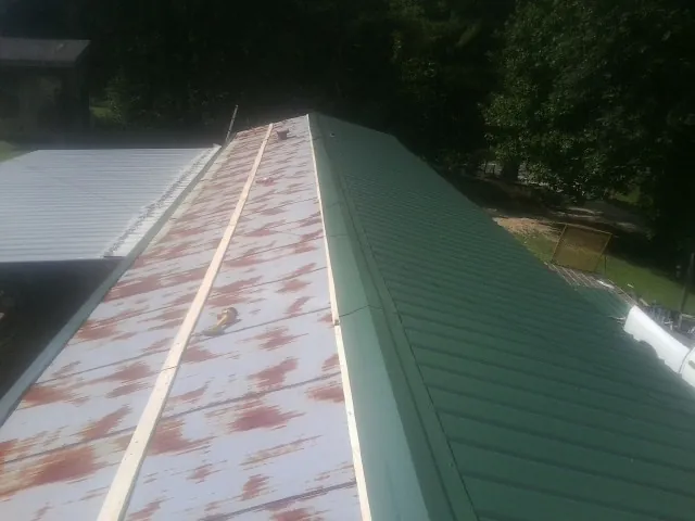 Old rusted panels beside newly installed green metal roofing — Wind Damage Roof Repair by Roofing Brothers in New Gloucester
