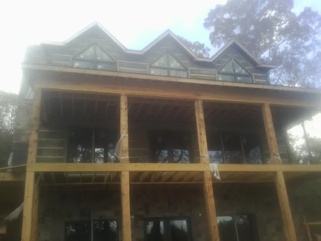 Dormers and porch framing on a large log home under construction — Roof Coating work by our crew in New Gloucester