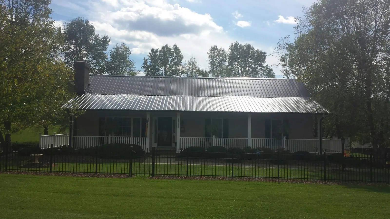 Gray metal roof on a brick ranch with a full width front porch — Gutter Guard Installation work by our crew in New Gloucester